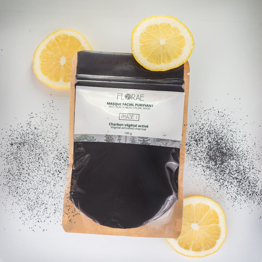 Sachet avec une fenêtre transparente en avant. On y voit la poudre noire. Présentation sur un fond blanc avec des tranches de citrons et de la poudre noire dispersée. Actifs pour masque facial. 